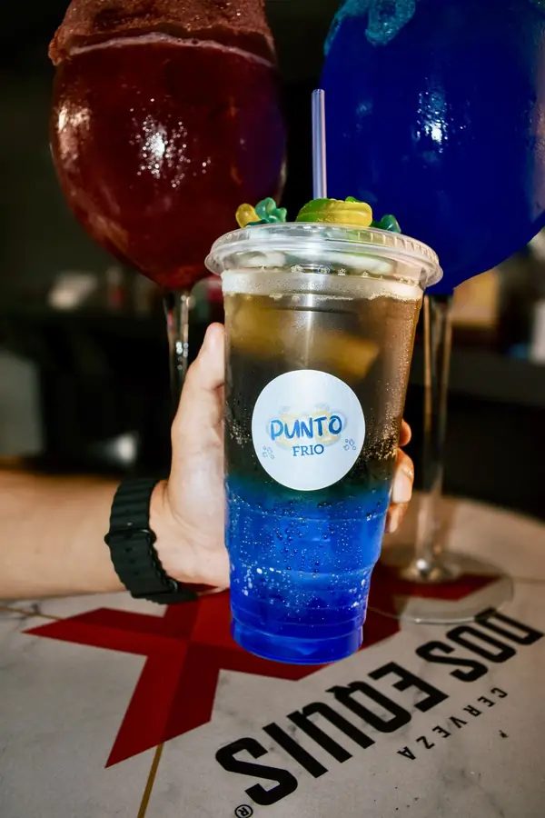 Vaso azul con el logo de Punto Frío en la mano
